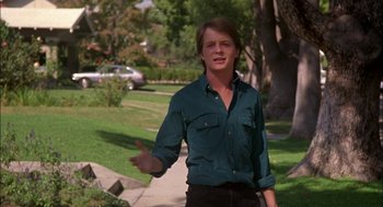 Movie still from “Teen Wolf” (1985), directed by Rod Daniel – A man in a green shirt is standing in the grass; Medium shot, Low angle