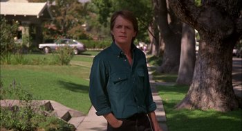 Movie still from “Teen Wolf” (1985), directed by Rod Daniel – A young man standing on a sidewalk near a park; Medium shot, Low angle