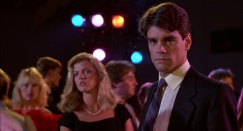 Movie still from “Teen Wolf” (1985), directed by Rod Daniel – A man and a woman standing in front of a crowd of people; Close Up shot, Low angle