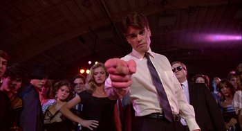 Movie still from “Teen Wolf” (1985), directed by Rod Daniel – A man in a white dress shirt and tie pointing at the camera; Medium shot, Low angle