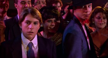 Movie still from “Teen Wolf” (1985), directed by Rod Daniel – A group of people standing around each other in a room; Close Up shot, Over the shoulder angle