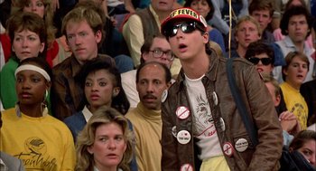 Movie still from “Teen Wolf” (1985), directed by Rod Daniel – A crowd of people sitting and standing in a room; Close Up shot, Low angle
