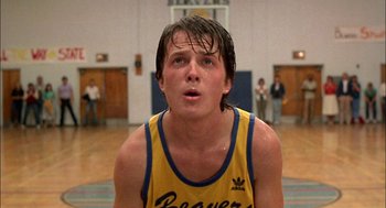 Movie still from “Teen Wolf” (1985), directed by Rod Daniel – A man in a yellow and blue shirt in a gym; Close Up shot, Low angle
