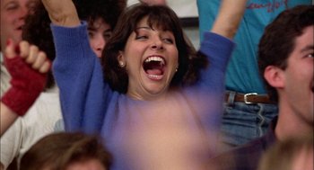 Movie still from “Teen Wolf” (1985), directed by Rod Daniel – A woman in a blue sweater is cheering; Close Up shot, Low angle