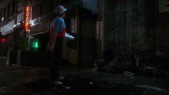 Movie still from “Teenage Mutant Ninja Turtles” (1990), directed by Steve Barron – A young boy holding a white frisbee in the dark; Wide shot, Low angle