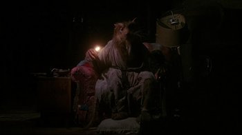 Movie still from “Teenage Mutant Ninja Turtles” (1990), directed by Steve Barron – A man sitting on a chair with a lamp in his hand; Medium shot, High angle