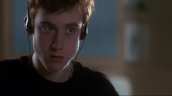 Movie still from “Teenage Mutant Ninja Turtles” (1990), directed by Steve Barron – A young man wearing a black t - shirt and headphones; Close Up shot, Over the shoulder angle