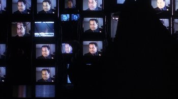 Movie still from “Teenage Mutant Ninja Turtles” (1990), directed by Steve Barron – A person is taking a picture of a man on a tv screen; Close Up shot, Over the shoulder angle