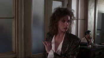 Movie still from “Teenage Mutant Ninja Turtles” (1990), directed by Steve Barron – A woman in a black and white jacket is standing in front of a window; Close Up shot, Over the shoulder angle