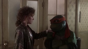 Movie still from “Teenage Mutant Ninja Turtles” (1990), directed by Steve Barron – A woman touching the head of a stuffed turtle; Medium shot, Over the shoulder angle