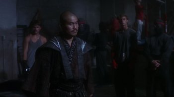 Movie still from “Teenage Mutant Ninja Turtles” (1990), directed by Steve Barron – A man with a bald head in a dark room; Medium shot, Over the shoulder angle
