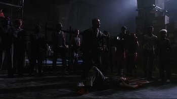 Movie still from “Teenage Mutant Ninja Turtles” (1990), directed by Steve Barron – A group of people standing around a man lying on the ground; Wide shot, Low angle