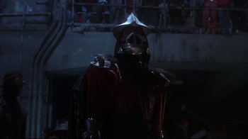Movie still from “Teenage Mutant Ninja Turtles” (1990), directed by Steve Barron – A person wearing a helmet and holding a sword; Medium shot, Low angle