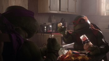 Movie still from “Teenage Mutant Ninja Turtles” (1990), directed by Steve Barron – A teenage mutant ninja turtle holding a sandwich in a kitchen; Medium shot, Low angle