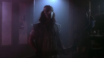 Movie still from “Teenage Mutant Ninja Turtles” (1990), directed by Steve Barron – A man with a mask on holding a knife; Medium shot, Low angle