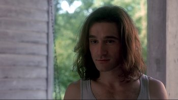 Movie still from “Teenage Mutant Ninja Turtles” (1990), directed by Steve Barron – A man with long hair is posing for a picture; Close Up shot, Over the shoulder angle