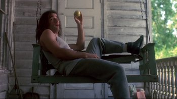 Movie still from “Teenage Mutant Ninja Turtles” (1990), directed by Steve Barron – A man holding an apple while sitting on top of a bench; Medium shot, Low angle