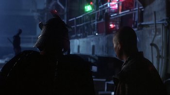 Movie still from “Teenage Mutant Ninja Turtles” (1990), directed by Steve Barron – Two people are standing next to each other in the dark; Medium shot, Over the shoulder angle
