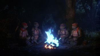 Movie still from “Teenage Mutant Ninja Turtles” (1990), directed by Steve Barron – A group of teenage mutant ninja turtles sitting around a fire; Wide shot, High angle