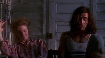 Movie still from “Teenage Mutant Ninja Turtles” (1990), directed by Steve Barron – Two women sitting in front of each other in front of a door; Medium shot, Low angle