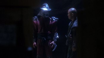 Movie still from “Teenage Mutant Ninja Turtles” (1990), directed by Steve Barron – Two men in costumes are standing in the dark; Medium shot, Over the shoulder angle