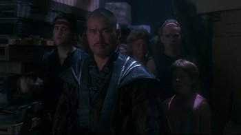 Movie still from “Teenage Mutant Ninja Turtles” (1990), directed by Steve Barron – A group of people standing in a dark room; Medium shot, Over the shoulder angle