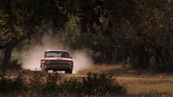 Movie still from “Temple Grandin” (2010), directed by Mick Jackson – An old car driving down a dirt road near a forest; Wide shot, Low angle