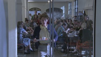 Movie still from “Temple Grandin” (2010), directed by Mick Jackson – A woman holding a tray of food in front of a group of diners; Wide shot, High angle