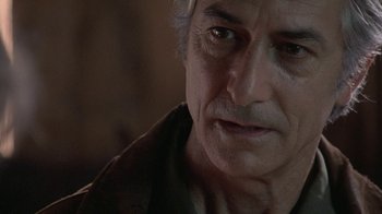 Movie still from “Temple Grandin” (2010), directed by Mick Jackson – An older man looking at the camera in a dark room; Close Up shot, Over the shoulder angle