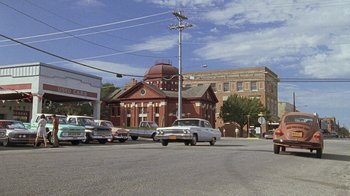 Movie still from “Temple Grandin” (2010), directed by Mick Jackson – Cars driving down the street in front of an old building; Extreme Wide shot, Low angle