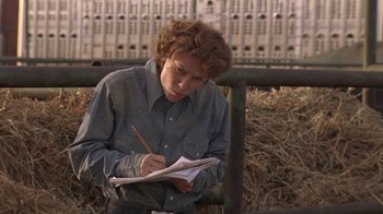 Movie still from “Temple Grandin” (2010), directed by Mick Jackson – A person writing on a piece of paper in front of a fence; Medium shot, Over the shoulder angle