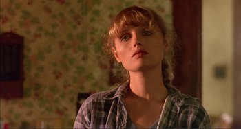 Movie still from “Tender Mercies” (1983), directed by Bruce Beresford – A young woman with blonde curly hair wearing a plaid shirt looking at the camera; Close Up shot, Low angle