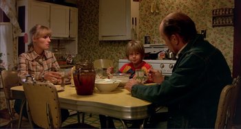 Movie still from “Tender Mercies” (1983), directed by Bruce Beresford – A man sitting at a table with a child in front of him; Medium shot, High angle
