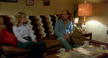 Movie still from “Tender Mercies” (1983), directed by Bruce Beresford – A man and a woman sitting on a couch in a living room; Wide shot, High angle
