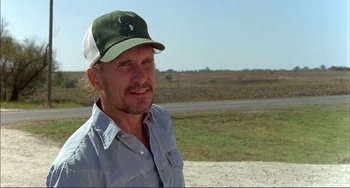 Movie still from “Tender Mercies” (1983), directed by Bruce Beresford – A person wearing a hat near a road; Close Up shot, Over the shoulder angle