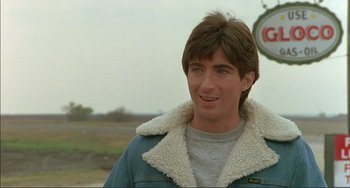 Movie still from “Tender Mercies” (1983), directed by Bruce Beresford – A young man in a blue jacket is smiling for the camera; Close Up shot, Over the shoulder angle