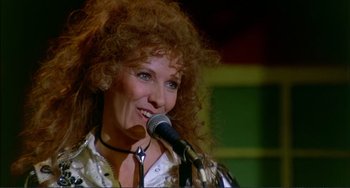 Movie still from “Tender Mercies” (1983), directed by Bruce Beresford – A person holding a microphone on a stage; Close Up shot, Low angle