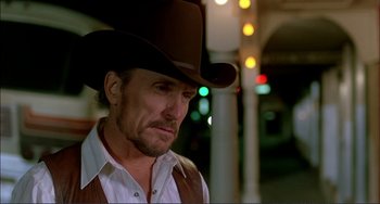 Movie still from “Tender Mercies” (1983), directed by Bruce Beresford – A man wearing a brown cowboy hat standing in front of a street light; Close Up shot, Low angle