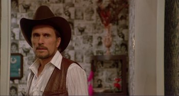 Movie still from “Tender Mercies” (1983), directed by Bruce Beresford – A man wearing a cowboy hat in front of a wall; Close Up shot, Over the shoulder angle
