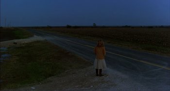 Movie still from “Tender Mercies” (1983), directed by Bruce Beresford – A woman standing on the side of a road at night; Extreme Wide shot, High angle