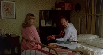 Movie still from “Tender Mercies” (1983), directed by Bruce Beresford – A man and a woman sitting on a bed playing a guitar; Medium shot, High angle