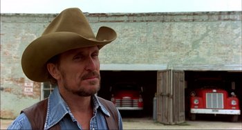 Movie still from “Tender Mercies” (1983), directed by Bruce Beresford – A man wearing a cowboy hat in front of an old car; Close Up shot, Low angle