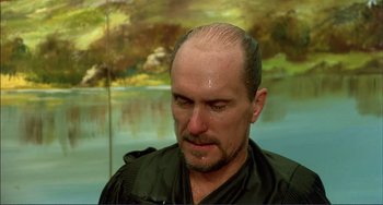 Movie still from “Tender Mercies” (1983), directed by Bruce Beresford – A man with a bald head is looking at the camera; Close Up shot, Over the shoulder angle