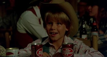 Movie still from “Tender Mercies” (1983), directed by Bruce Beresford – A boy in a cowboy hat holding two cans of dr; Close Up shot, High angle