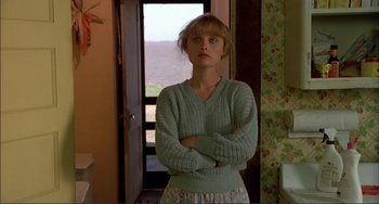 Movie still from “Tender Mercies” (1983), directed by Bruce Beresford – A woman standing in front of a window with her arms crossed; Medium shot, Low angle