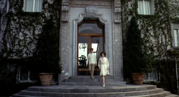 Movie still from “Teorema” (1968), directed by Pier Paolo Pasolini – A man and a woman standing in front of an entrance to a building; Wide shot, Low angle