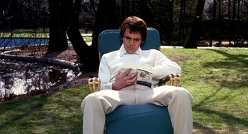 Movie still from “Teorema” (1968), directed by Pier Paolo Pasolini – A man sitting in a chair reading a book; Medium shot, High angle