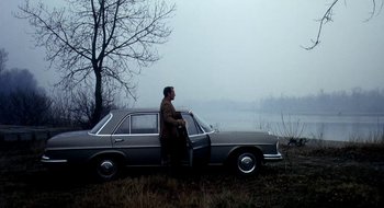 Movie still from “Teorema” (1968), directed by Pier Paolo Pasolini – A man sitting on the hood of a car in a field; Wide shot, Low angle