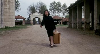 Movie still from “Teorema” (1968), directed by Pier Paolo Pasolini – A woman walking down a dirt road holding a suitcase; Wide shot, Low angle