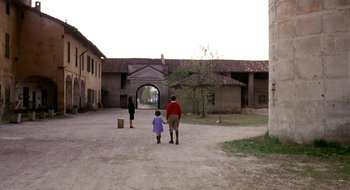 Movie still from “Teorema” (1968), directed by Pier Paolo Pasolini – A man and a little girl walking down a dirt road; Wide shot, High angle